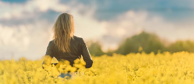 Image d'une femme de dos dans un champ de fleur jaune